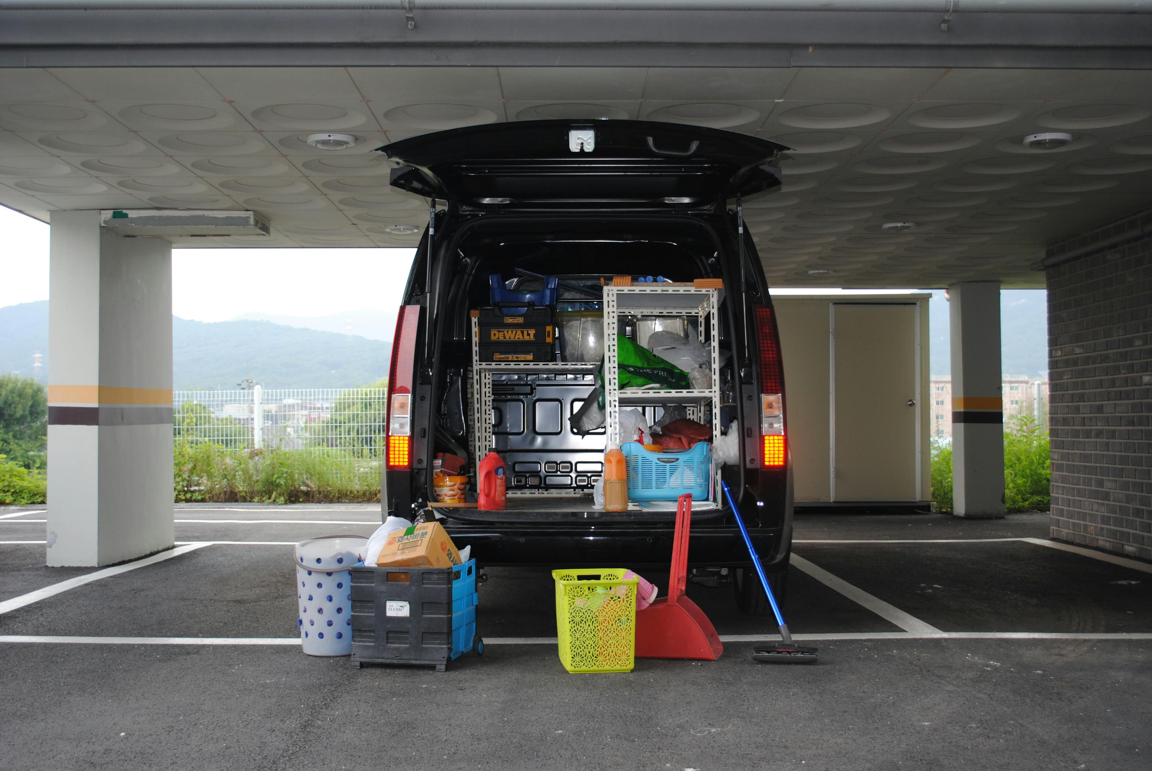 A black van parked in a garage with its back doors open, displaying various tools and cleaning equipment.
